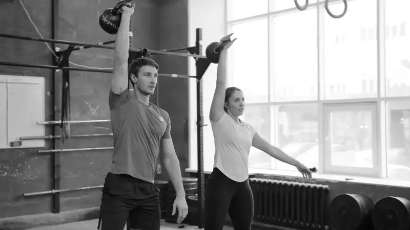 Dupla treinando kettlebell perto da janela