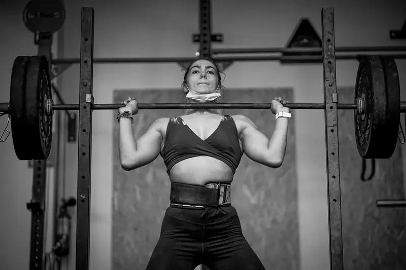 Aluna da Cambirela Box segurando a barra na posição de front squat, em preto e branco