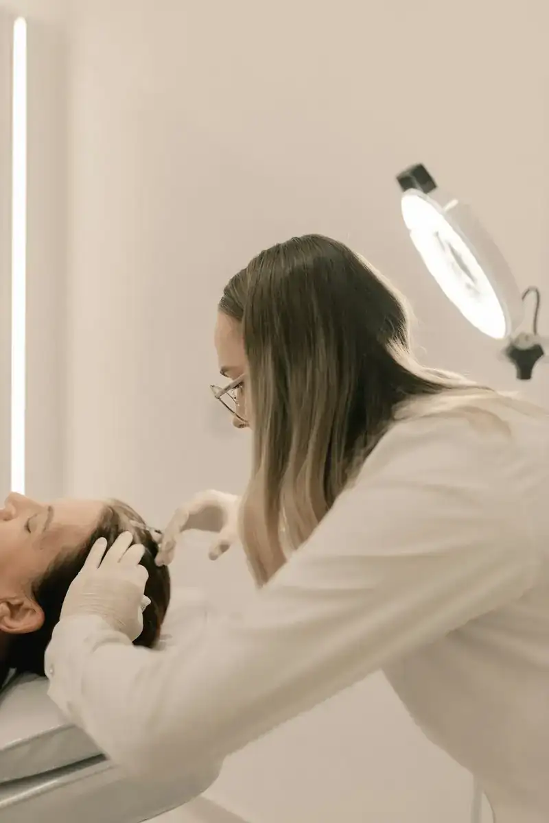 Lívia atendendo uma cliente deitada na maca, com luminária de aumento