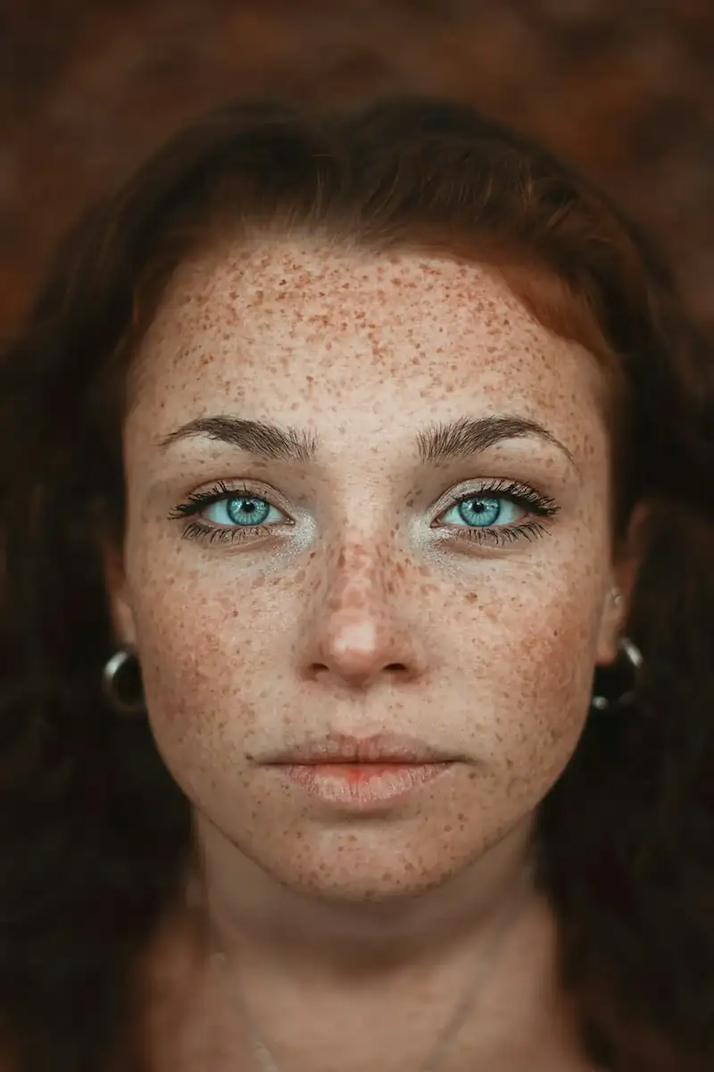 Retrato de mulher ruiva com sardas, pele sem maquiagem, fundo marrom