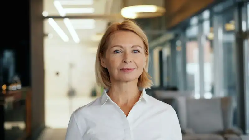 Helena Rothbarth, corretora e sócia, de camisa branca em um living iluminado