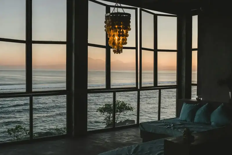 Sala com janelões abertos para o mar ao entardecer