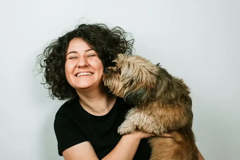 Tutora rindo enquanto o cão lambe o rosto dela